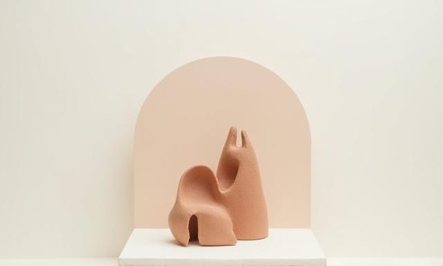 Abstract desert-inspired ceramic sculpture with earthy textures and natural tones on a minimalist display.